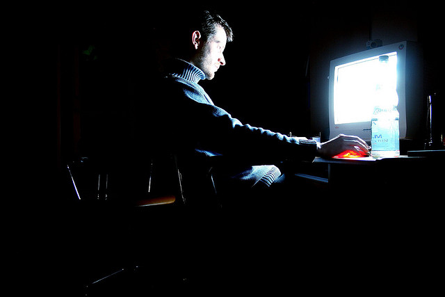 man using computer in dark room screen glow privacy security