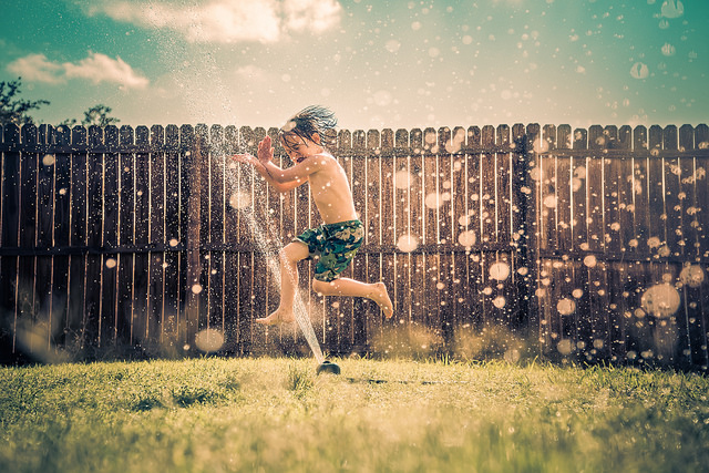 boy running through sprinker backyard hydration system