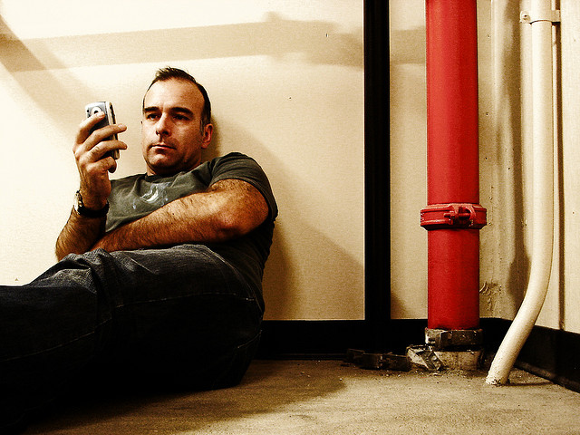 waiting for phone to load update bored boredom man sitting against wall pipes